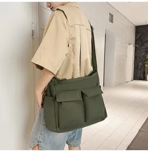 A man wearing a large olive green padded messenger bag in a minimalist white hallway
