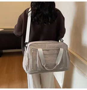 Back view of a large grey nylon travel bag carried by a person in a casual setting
