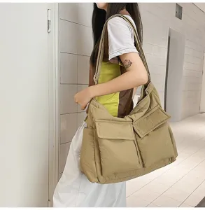 Large khaki canvas messenger bag with front pockets, side view detail shown on a model.
