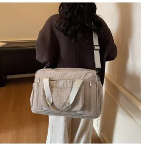 Detail showing a woman carrying a large capacity beige nylon travel bag for gym or weekend use