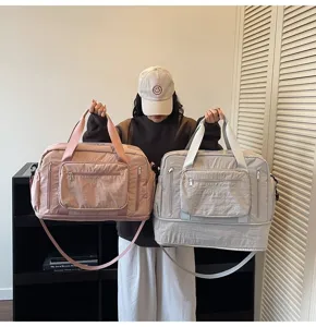 Large capacity expandable travel bags in pink and grey held by a model