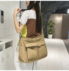 Large khaki vintage canvas messenger bag worn by a model in a modern indoor setting