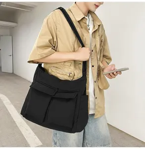 Close-up of a large black padded messenger bag worn by a model in a casual outfit