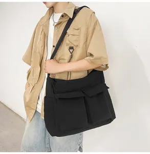 Large black canvas messenger bag featuring double front pockets shown on male model