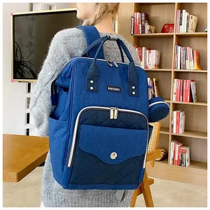 Elegante mochila de pañales de lona azul para mamás con bolsillo acolchado y asas superiores.