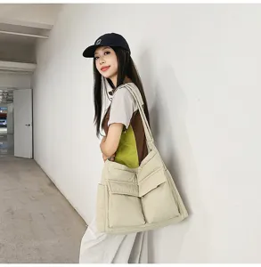 Asian female model wearing a large beige canvas crossbody bag in a minimalist hallway