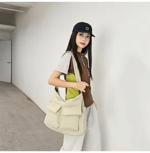 Asian model wearing a beige large capacity canvas messenger bag in a minimalist setting
