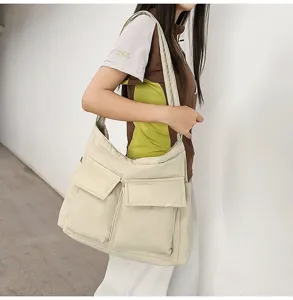 Side view of a large cream canvas messenger bag worn by a model in a minimalist setting