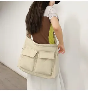 Large beige canvas messenger bag with double front pockets shown on female model