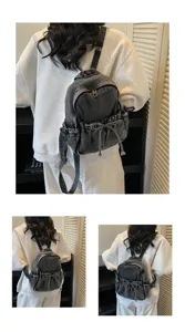 Vue arrière d'un mini sac à dos tendance en denim noir avec détail de nœud coulissant