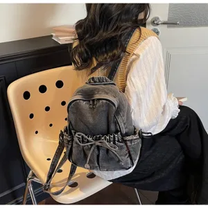 Vue arrière d'une femme portant un mini sac à dos en jean délavé avec nœud papillon.