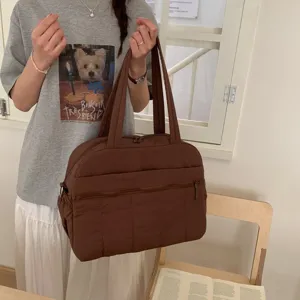 Lifestyle shot of a large brown quilted puffer travel bag for women, ideal for gym use.