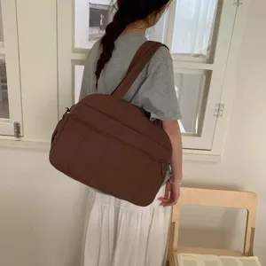 Large capacity brown quilted puffer fitness travel bag carried on a female model shoulder