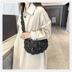 Detail van een zwarte bubbelwolk-tas gedragen bij een stijlvolle beige trenchcoat
