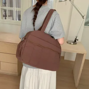Close-up detail of large brown quilted cloud bag worn over the shoulder by a female model