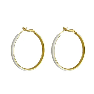 Large gold-plated hoop earrings with white enamel finish for a minimalist chic look.