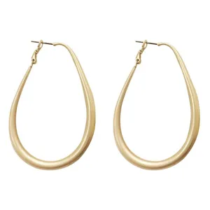 Close-up detail of matte gold oversized teardrop hoop earrings with a minimalist design.