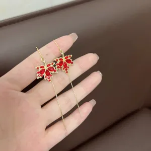 Detailed view of elegant red maple leaf earrings with long gold tassel and rhinestones