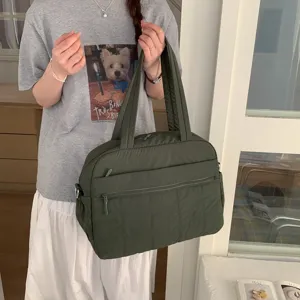 Lifestyle shot of a model carrying a large dark green quilted cloud travel bag for scale