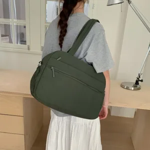 Lifestyle view of a dark green large capacity quilted travel bag carried on shoulder
