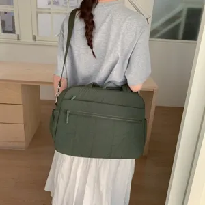 Large capacity olive green quilted travel bag shown being carried as a shoulder bag