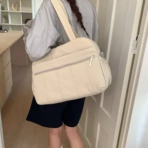 Large beige quilted cloud travel bag carried by a woman in a lifestyle setting