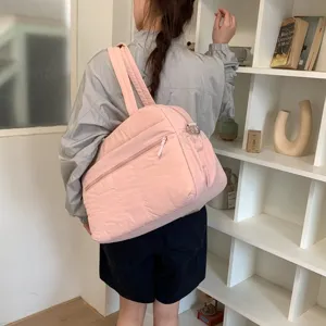 Large pink puffy cloud travel bag for women shown on shoulder in lifestyle scene