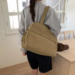 Spacious khaki puffy travel duffle bag carried by a model in a bright room setting