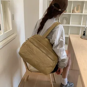Large capacity khaki travel fitness bag shown on shoulder in a minimalist room setting