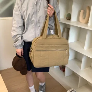 Asian woman carrying a large khaki quilted travel bag in a modern indoor lifestyle scene