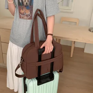Large brown quilted travel duffel bag for women featuring trolley sleeve on mint suitcase