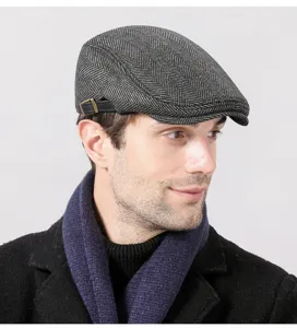 Close-up of men's grey herringbone flat cap with adjustable leather strap detail.