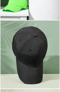 Detailed view of a black quick-dry baseball cap against a sage green textured background