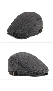 Close-up detail of grey herringbone flat cap featuring adjustable black leather side strap