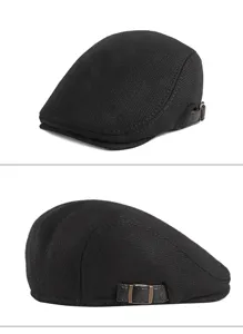 Detail view of a black flat cap showing the textured fabric and adjustable leather side strap.