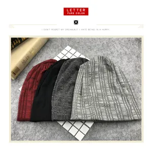 Juego de cuatro gorros de punto suave en tonos rojo, negro y gris sobre fondo texturizado.