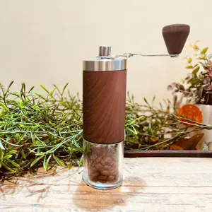 Detail of manual coffee grinder with wood grain finish and stainless steel crank.