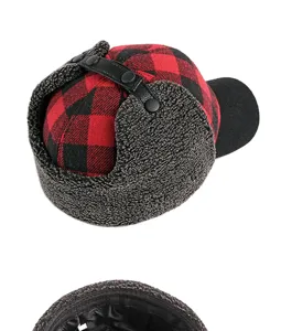 Close-up of red and black plaid winter trapper hat with warm fleece ear flaps and quilted lining