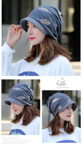 Detailed view of a grey autumn brimmed beanie with gold feather print on a woman.