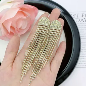 Exquisite long gold rhinestone tassel earrings held for detailed close-up display