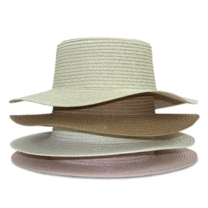 Quattro cappelli di paglia da donna a testa piatta in beige, kaki, bianco e rosa per il sole.