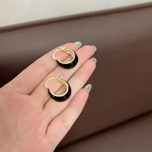 Detail showing vintage U-shaped hoop earrings with black enamel and gold-plated finish