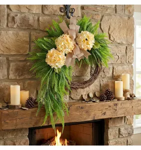 Rustic hydrangea wreath with fern greenery and burlap bow on a stone fireplace
