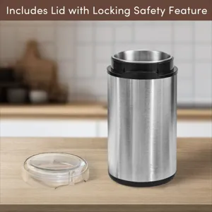 Close-up view of a stainless steel electric coffee grinder with its detached safety locking lid