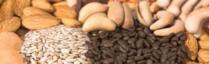 Close-up of coffee beans and nuts for grinding including almonds and sunflower seeds.
