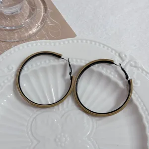 Close-up of geometric hoop earrings with tan and black dual-tone design