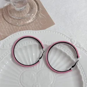Close-up of pink and black two-tone large geometric hoop earrings on a plate