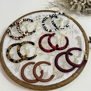 Variety of vintage leopard and leather-wrapped hoop earrings displayed on white lace