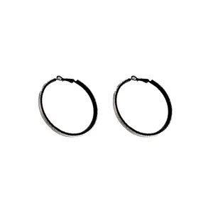 Macro detail of oversized black textured hoop earrings featuring silver-tone glitter edges.
