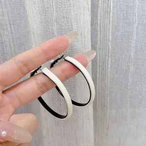 Chic black and white geometric hoop earrings held by hand for a bold fashion statement